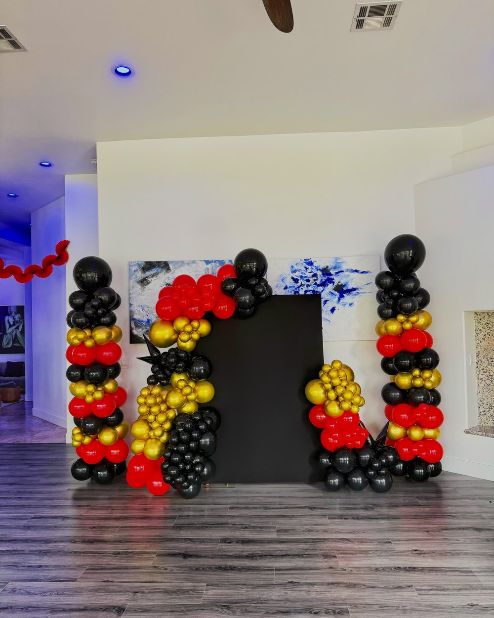 Indoor setup with red, yellow and black balloon columns flanking a dark backdrop