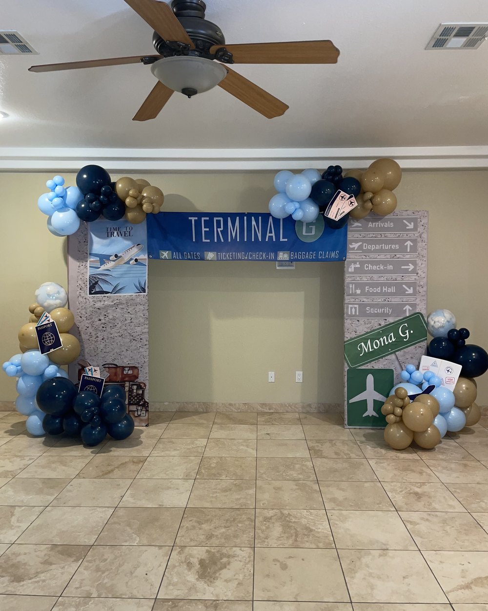 Travel themed setup with a terminal sign, boarding pass props and navy and gold balloons